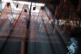 Incense and long circular sticks are burning in a temple