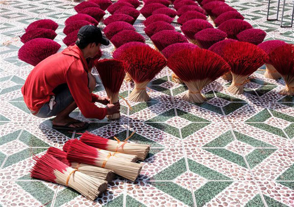 A young man is collecting dry incense sticks. After being dyed, these small bamboo sticks will be sun-dried